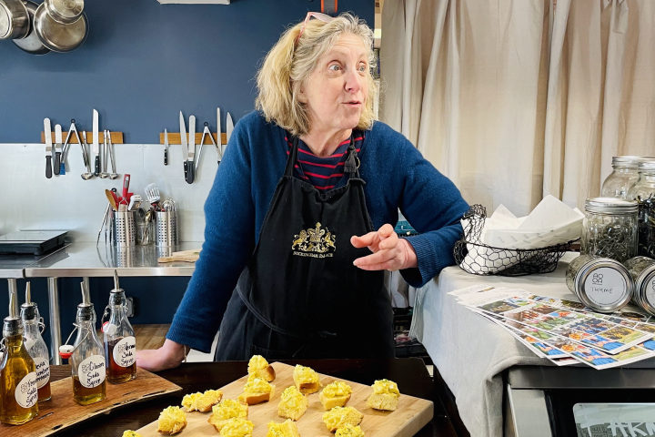 a woman standing behind a board of bread