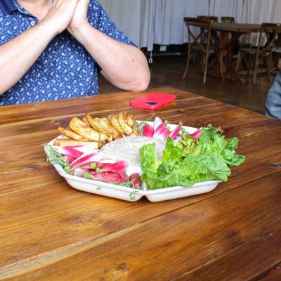 a person sitting on top of a wooden cutting board with a cake