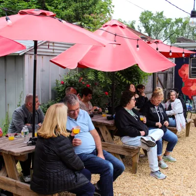 a group of people sitting at a picnic table and umbrella